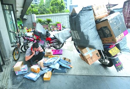 沙坪坝区沙滨路,快递员正在小区外通知业主来领取包裹。